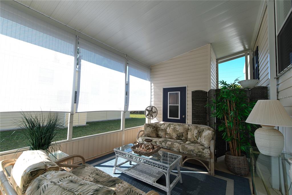 A screened-in porch features wicker furniture, a glass coffee table, and white roll-down shades — 9 HOLLAND DRIVE, PUNTA GORDA, FL