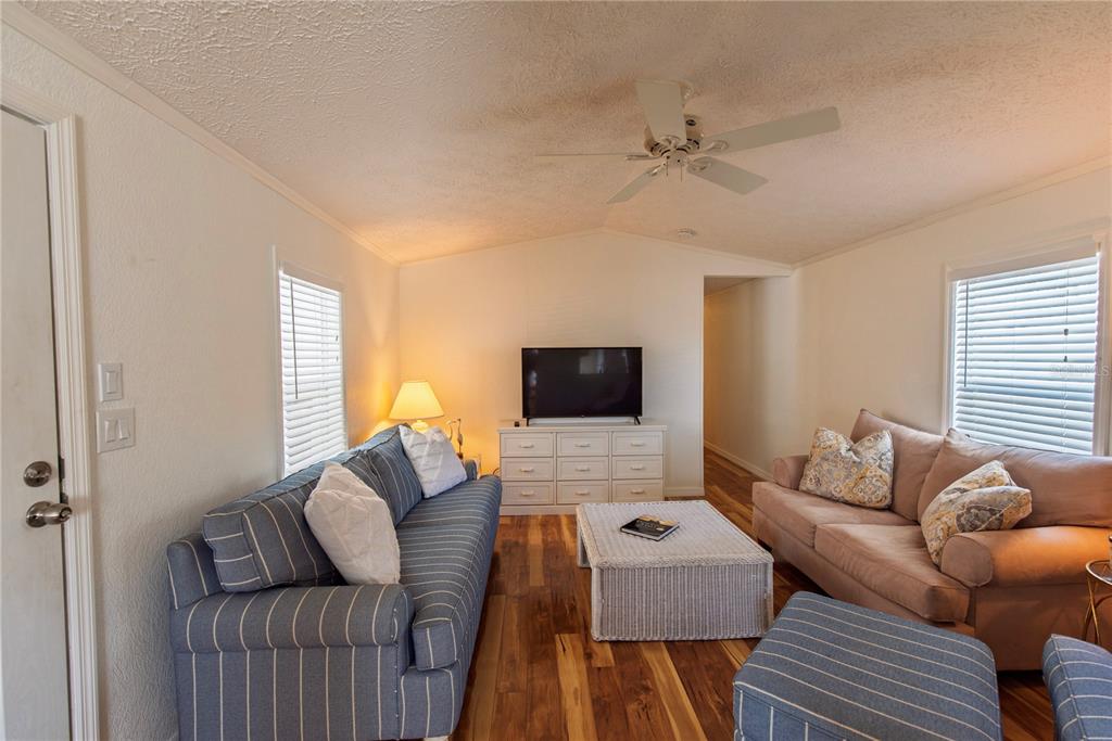 A living room features a striped sofa, a tan sofa, a white coffee table, and wood flooring — 9 HOLLAND DRIVE, PUNTA GORDA, FL