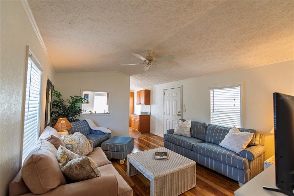 A living room features blue striped sofas, a wicker coffee table, and wood flooring — 9 HOLLAND DRIVE, PUNTA GORDA, FL