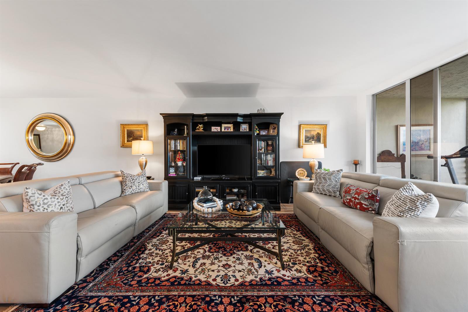 A living room features two light-colored leather sofas, a central glass coffee table, and an entertainment center — 3499 Oaks Way # 407, Pompano Beach FL 33069, POMPANO BEACH, FL