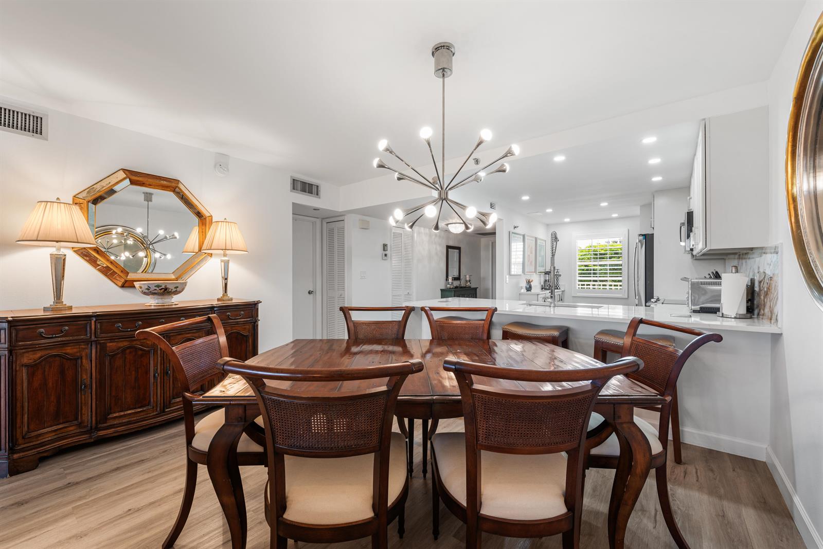 A dining area with a wooden table and chairs sits adjacent to a modern kitchen — 3499 Oaks Way # 407, Pompano Beach FL 33069, POMPANO BEACH, FL
