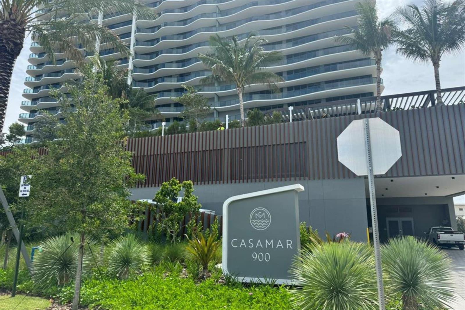 A modern high-rise building with wavy balconies stands behind a sign labeled Casamar 900 — 900 N Ocean Boulevard, Pompano Beach FL 33062, POMPANO BEACH, FL