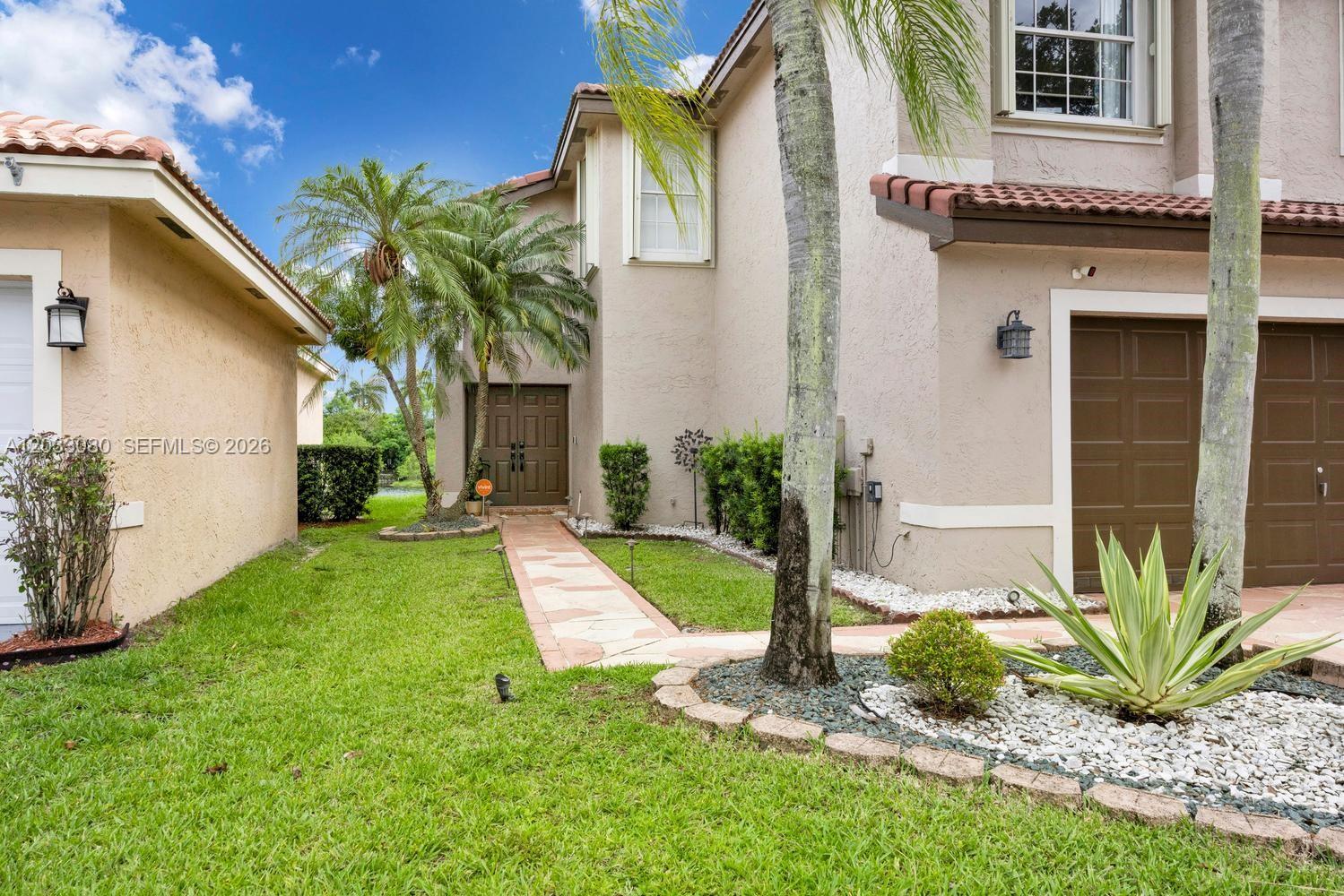 A two-story house exterior features a stone walkway, brown double doors, and a garage — 18018 SW 30th Ct, Miramar FL 33029, MIRAMAR, FL