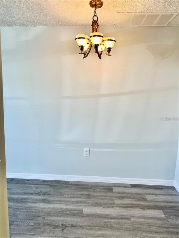 A dining area features a light fixture, a single wall outlet, and gray wood-look flooring — 4930 GETNER STREET, NEW PORT RICHEY, FL