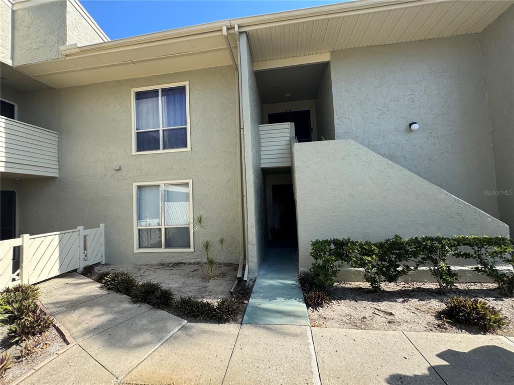 A two-story stucco apartment building exterior features a concrete walkway and a shared staircase — 621 WINDRUSH BAY DRIVE UNIT 621, TARPON SPRINGS, FL