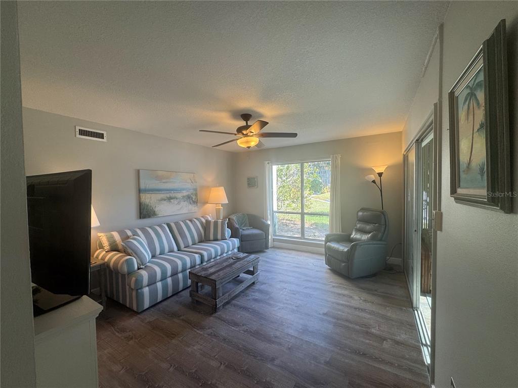 A living room features a striped sofa, a wooden coffee table, and a grey recliner — 621 WINDRUSH BAY DRIVE UNIT 621, TARPON SPRINGS, FL