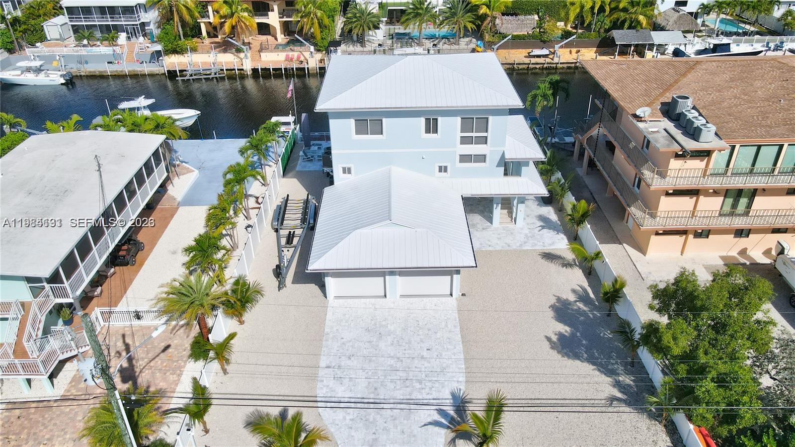 An aerial view shows a light blue house with a metal roof and gravel driveway — 48 S Andros Rd, Key Largo FL 33037, KEY LARGO, FL