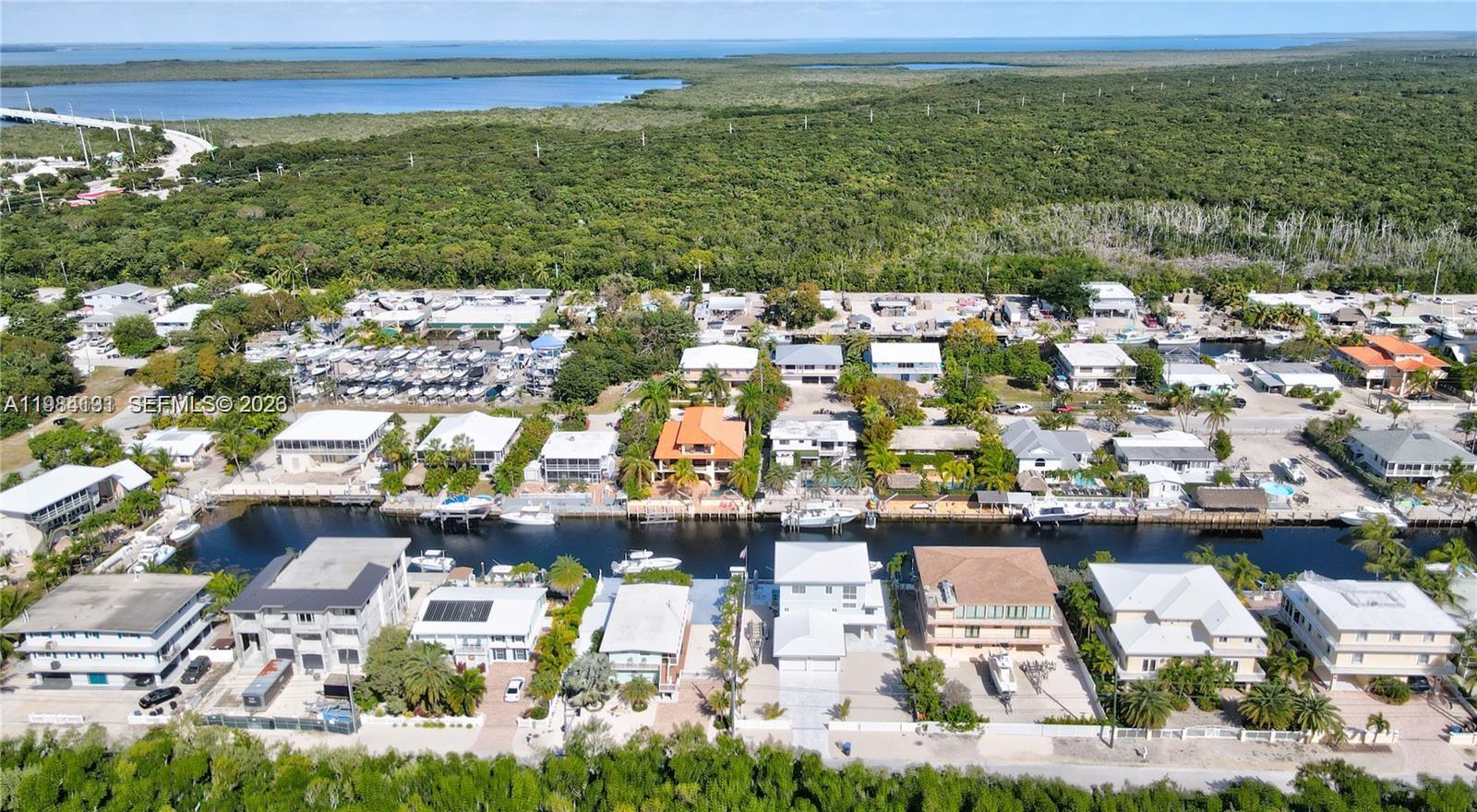 An aerial view shows waterfront houses along a canal with boats and dense surrounding vegetation — 48 S Andros Rd, Key Largo FL 33037, KEY LARGO, FL