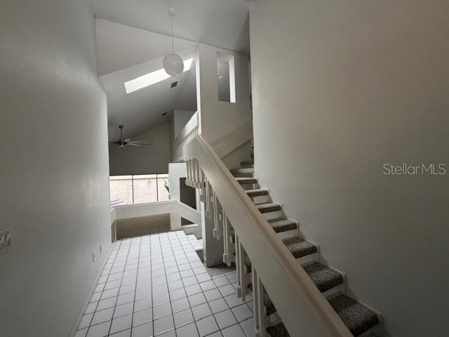 A staircase with carpeted steps and a white railing leads upward in a tiled entryway — 28 CASARENA COURT, WINTER HAVEN, FL