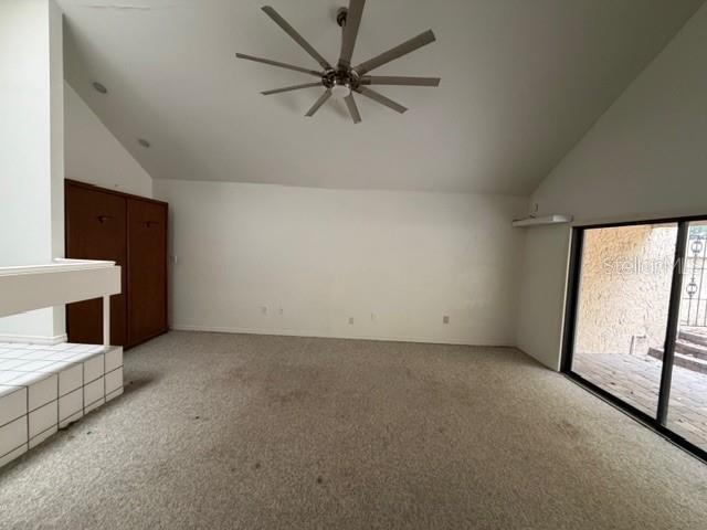 A carpeted room features a vaulted ceiling with a large fan and a sliding glass door — 28 CASARENA COURT, WINTER HAVEN, FL