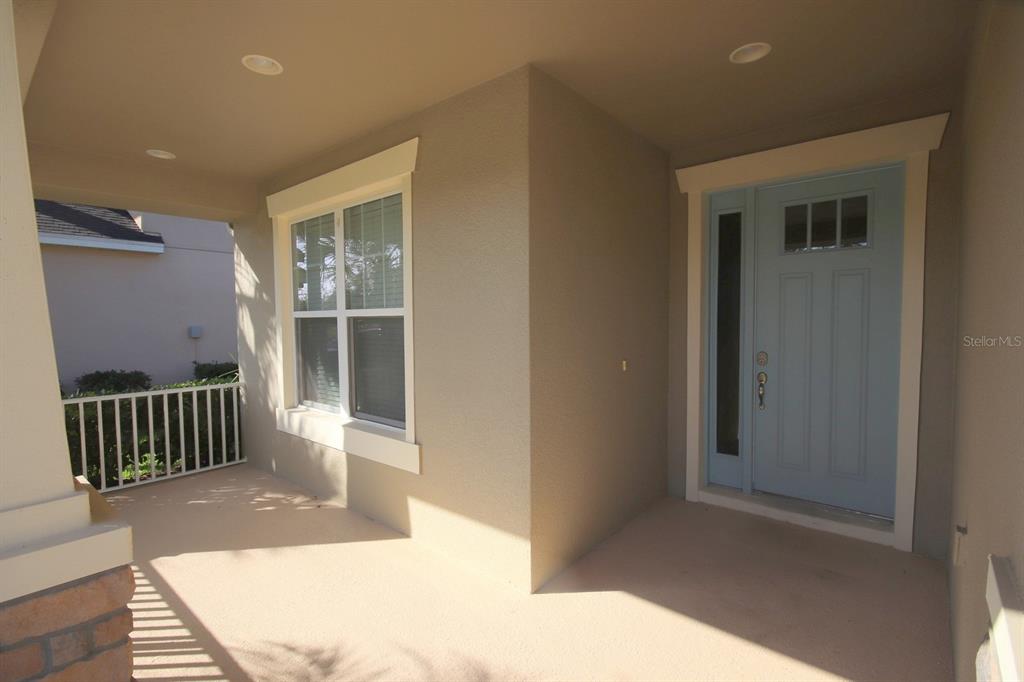A covered front porch features a light blue door, a window, and a white railing — 8827 SENTIERO DRIVE, LAND O LAKES, FL