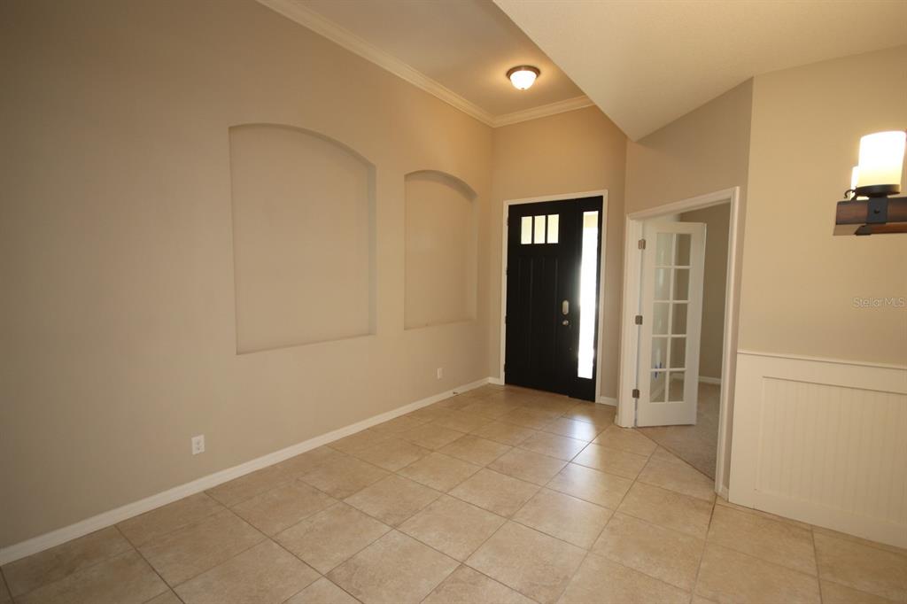 An entryway with tile flooring, two arched wall niches, and a black front door — 8827 SENTIERO DRIVE, LAND O LAKES, FL