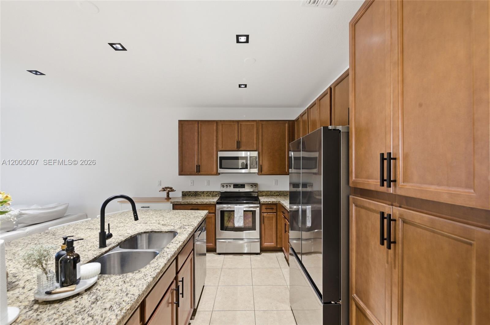A kitchen features wood cabinets, granite countertops, stainless steel appliances, and a central island — 6320 S Station Sq, Davie FL 33314, DAVIE, FL