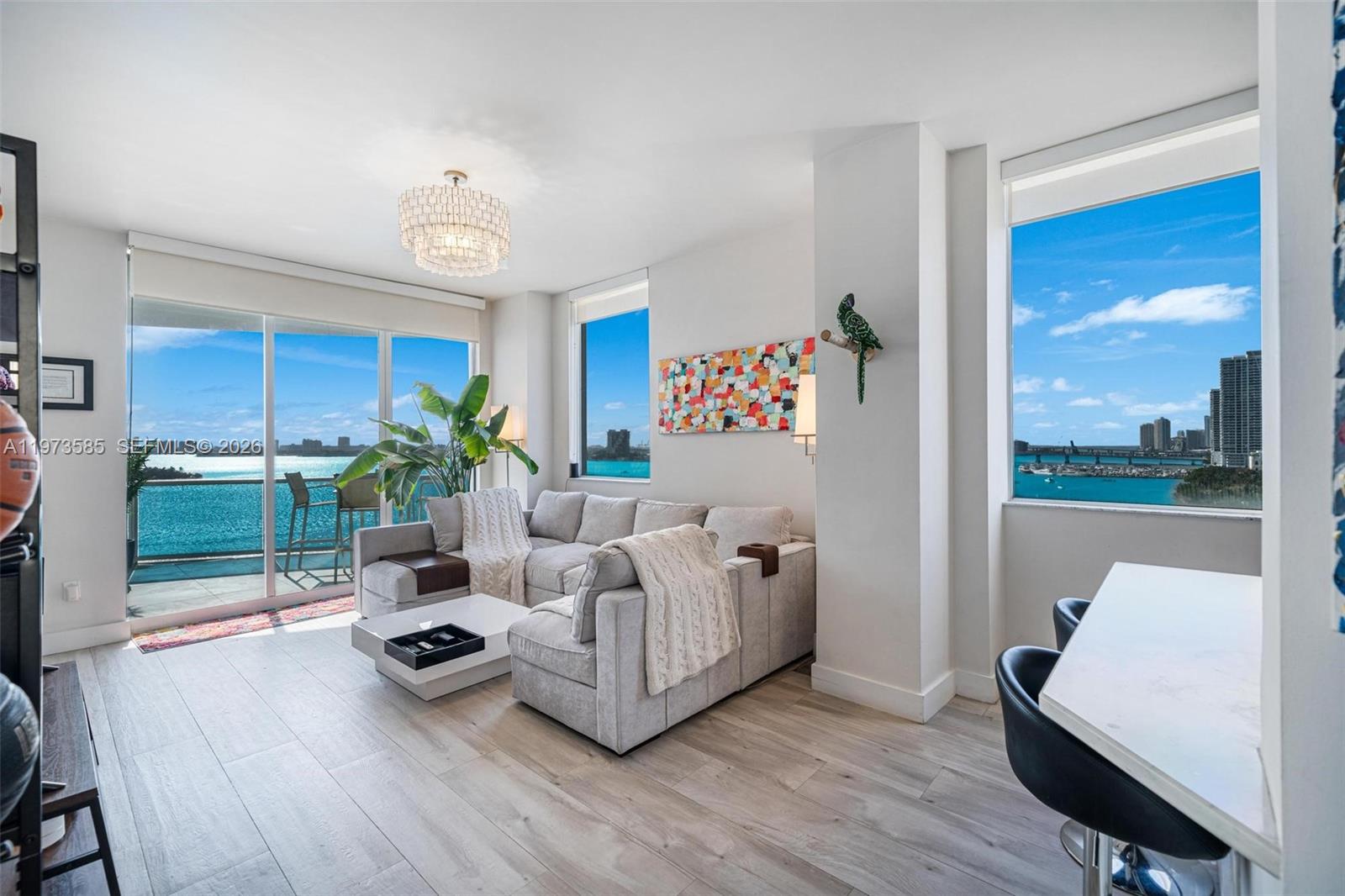 A living room features a sectional sofa, a white coffee table, and panoramic water views — 725 NE 22nd St # 10A, Miami FL 33137, MIAMI, FL