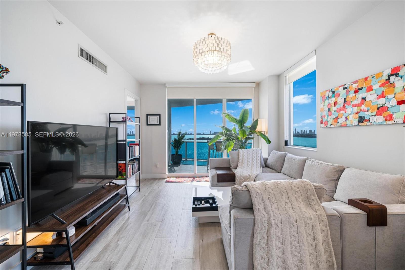 A living room features a sectional sofa, television, and large windows overlooking the ocean — 725 NE 22nd St # 10A, Miami FL 33137, MIAMI, FL