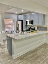 A modern kitchen features light gray cabinets, a white quartz countertop, and wood-look flooring — 7605 NW 4th Pl # 206, Margate FL 33063, MARGATE, FL
