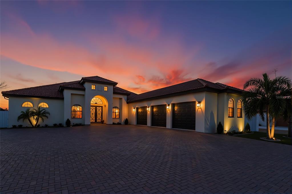 A single-story house with a tiled roof, three-car garage, and paved driveway at sunset — 7505 27TH AVENUE W, BRADENTON, FL