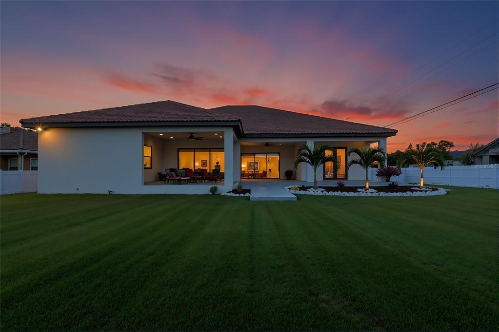 The rear exterior of a single-story house features a covered patio and a large lawn — 7505 27TH AVENUE W, BRADENTON, FL