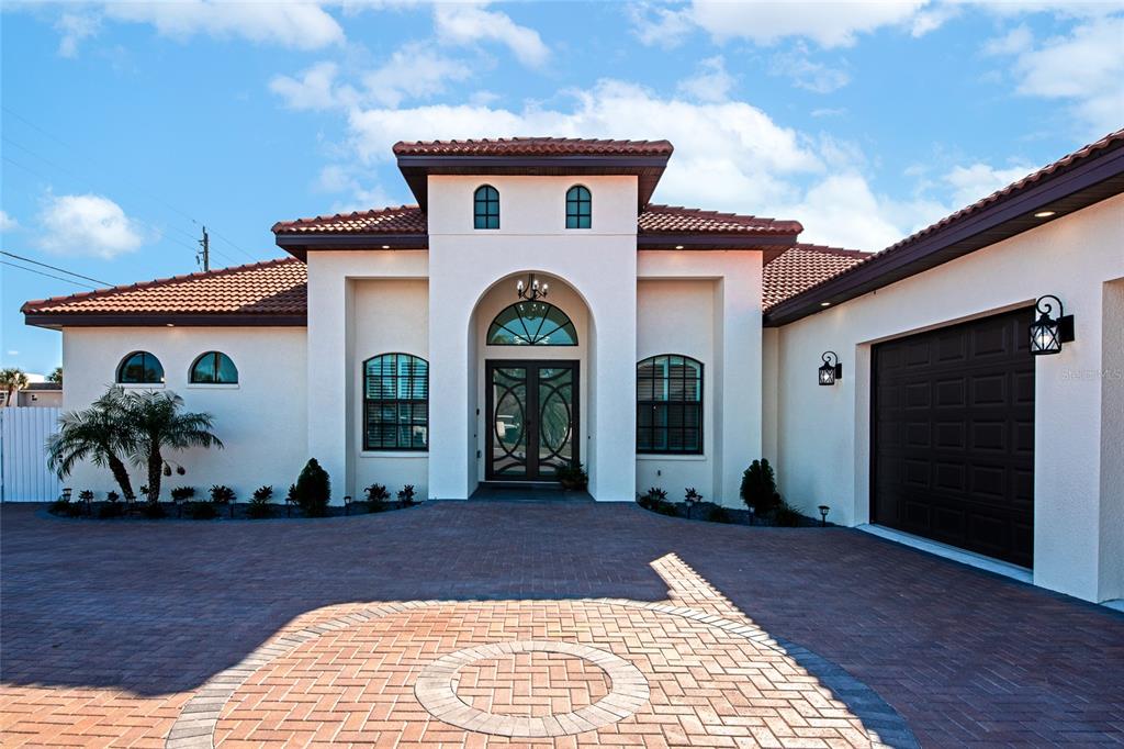 The exterior of a stucco home features a tiled roof, arched windows, and a paver driveway — 7505 27TH AVENUE W, BRADENTON, FL