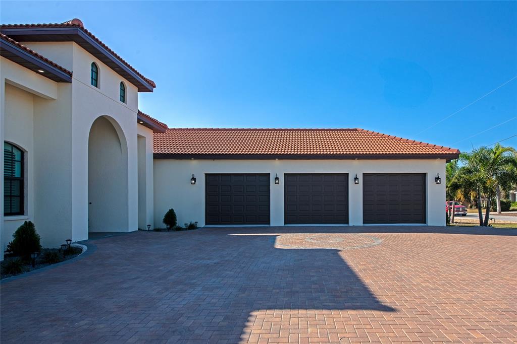A beige house with a three-car garage and a brick paver driveway — 7505 27TH AVENUE W, BRADENTON, FL