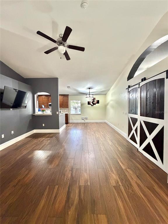 A living room features wood-look flooring, a vaulted ceiling, and sliding barn doors — 6436 FIG LEAF STREET, ST CLOUD, FL