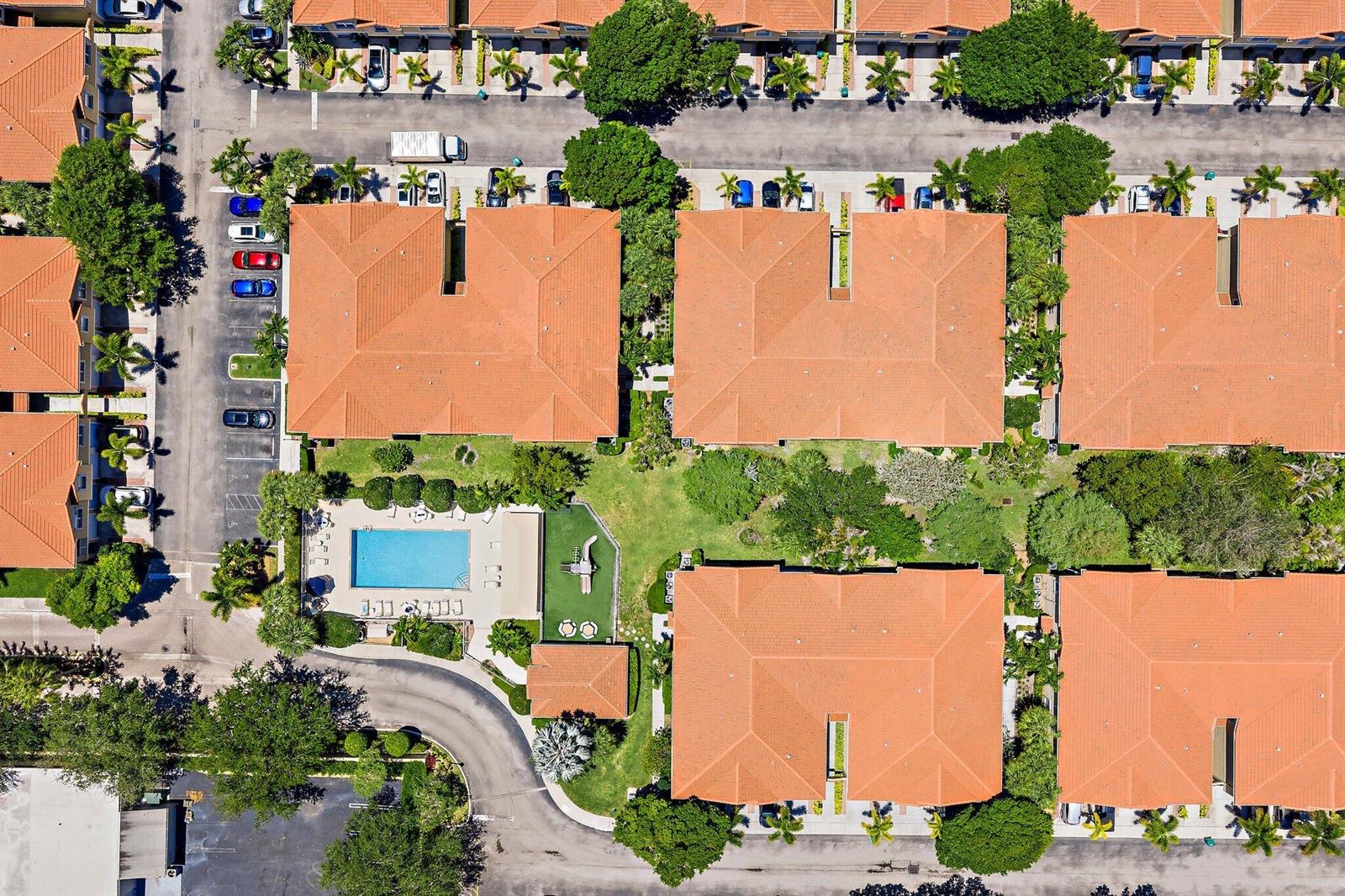 An aerial view shows a residential complex with terracotta-roofed buildings, a swimming pool, and landscaping — 114 Lighthouse Circle Unit C, Tequesta FL 33469, TEQUESTA, FL