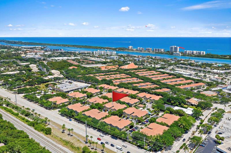 An aerial view shows a residential complex with terracotta-roofed buildings near a coastal waterway — 114 Lighthouse Circle Unit C, Tequesta FL 33469, TEQUESTA, FL