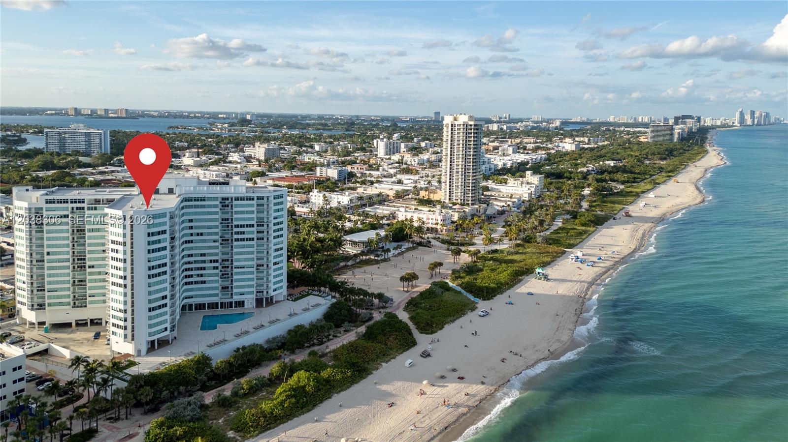 An aerial view shows a white high-rise condominium building situated next to a sandy beach — 7135 Collins Ave # 1216, Miami Beach FL 33141, MIAMI BEACH, FL