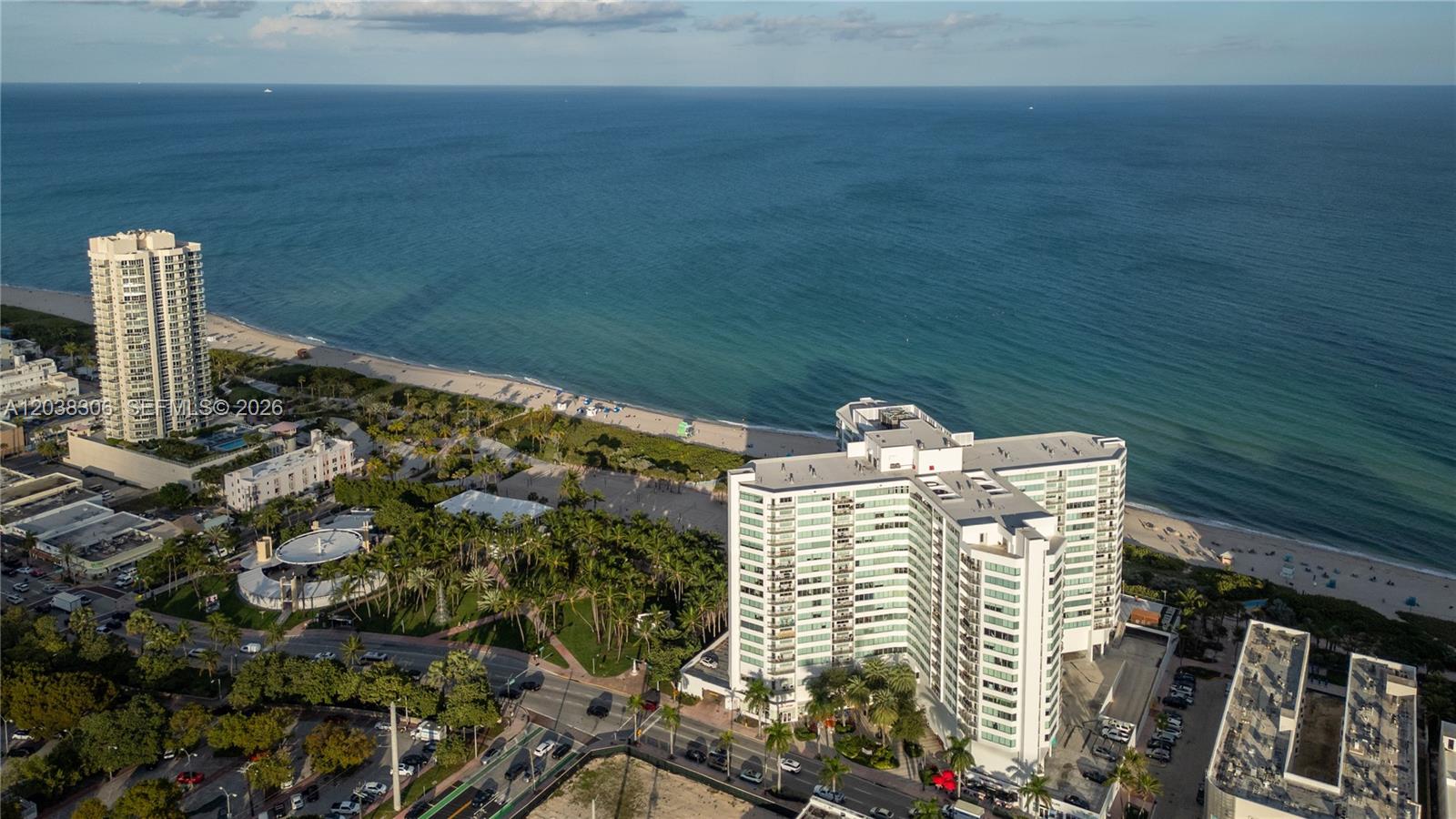 An aerial view shows two high-rise residential buildings situated along a sandy beach — 7135 Collins Ave # 1216, Miami Beach FL 33141, MIAMI BEACH, FL