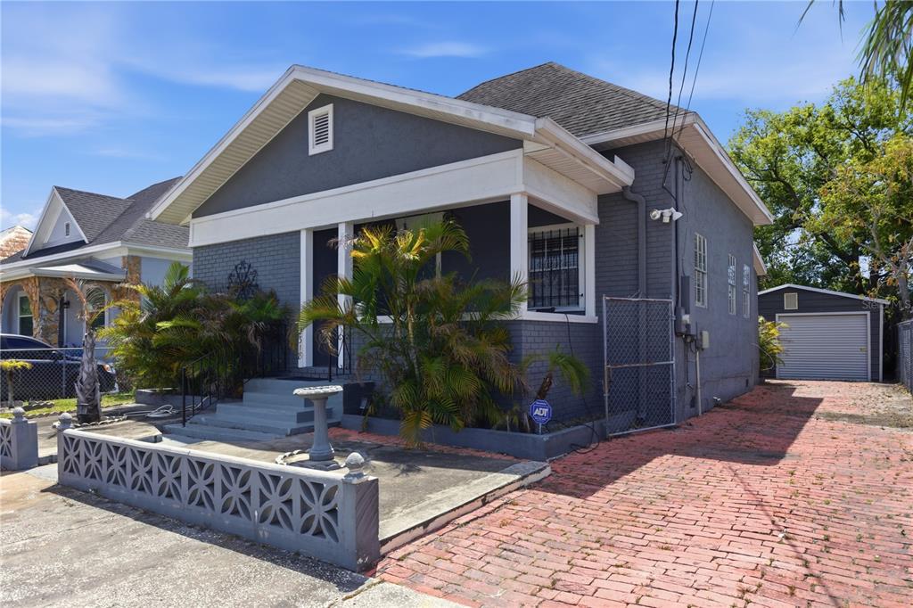 A gray brick house with a front porch, a brick driveway, and a detached garage — 2318 W CORDELIA STREET, TAMPA, FL