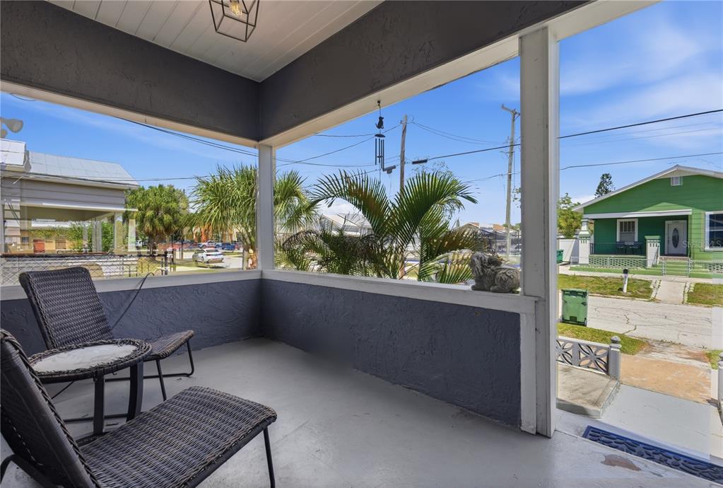 A covered porch features gray walls, two wicker chairs, and a view of the street — 2318 W CORDELIA STREET, TAMPA, FL