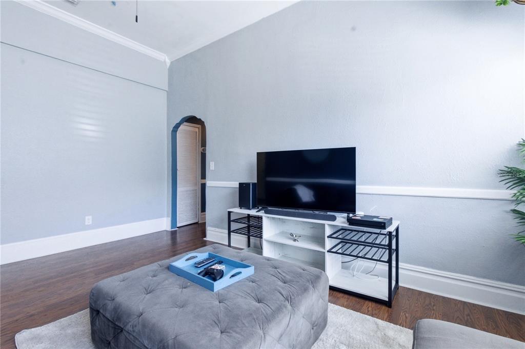 A living room features a television on a white stand, a gray ottoman, and hardwood floors — 2318 W CORDELIA STREET, TAMPA, FL