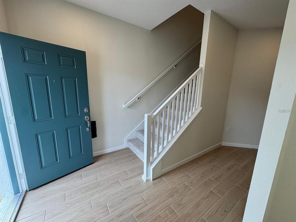 An entryway features a teal front door, light wood-look tile flooring, and a carpeted staircase — 486 LADY PALM STREET, APOPKA, FL