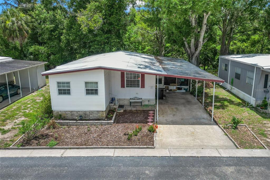 A single-story mobile home with a white exterior, a carport, and a front garden — 15601 LAKESHORE VILLA LOOP, TAMPA, FL