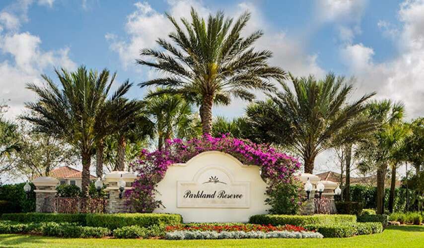 A stone monument sign for Parkland Reserve sits amidst palm trees and blooming bougainvillea — 7430 NW 109th Way, Parkland FL 33076, PARKLAND, FL