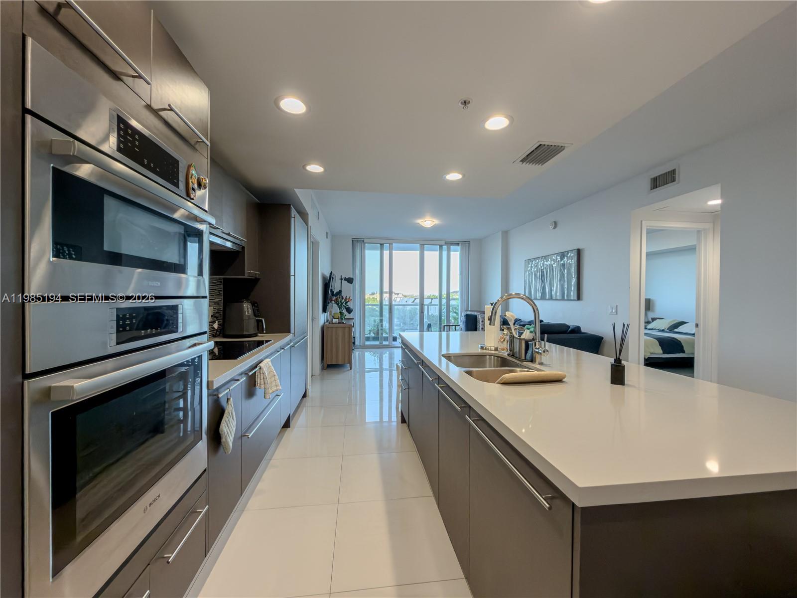 A modern kitchen features dark cabinetry, stainless steel appliances, and a large white island — 7825 NW 107th Ave # 301, Doral FL 33178, DORAL, FL
