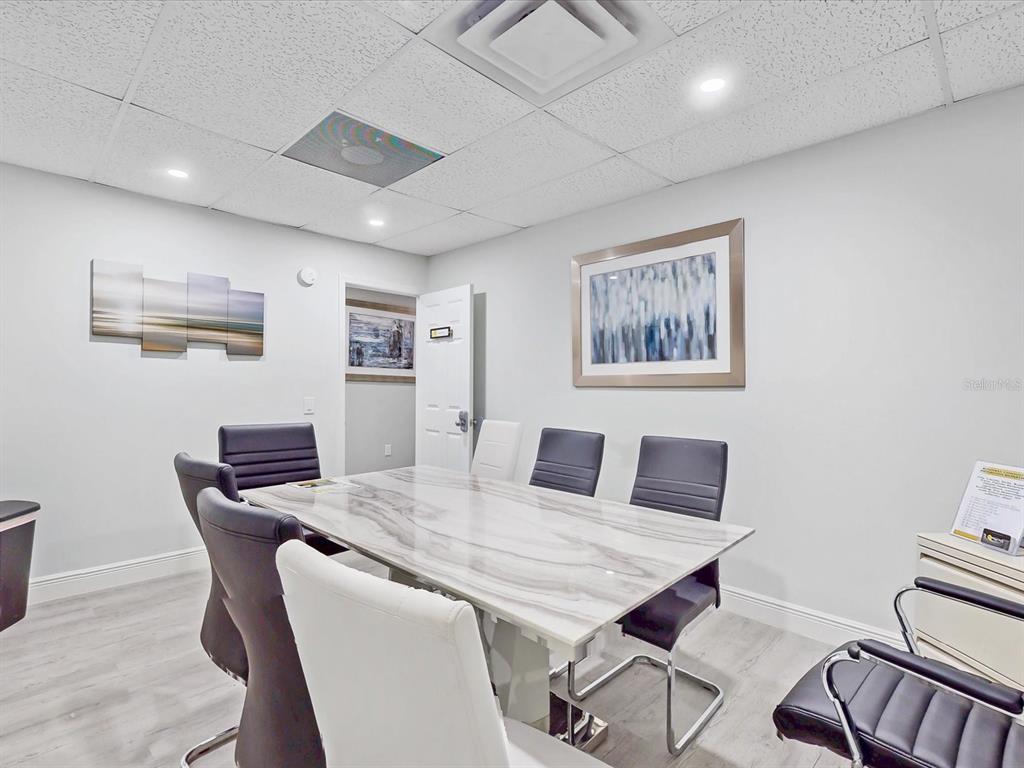 A conference room features a marble-topped table, modern chairs, and framed artwork on the walls — 18 W BASS STREET, KISSIMMEE, FL