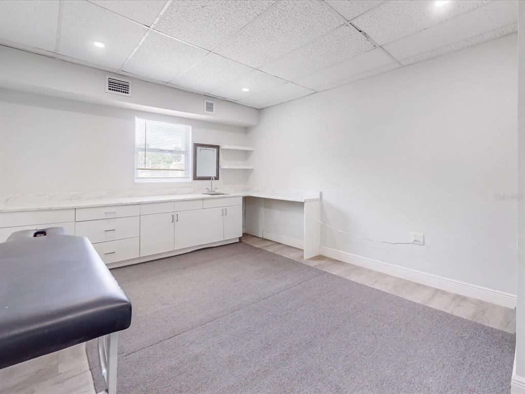 A room with white cabinets, a sink, a massage table, and a drop ceiling — 18 W BASS STREET, KISSIMMEE, FL