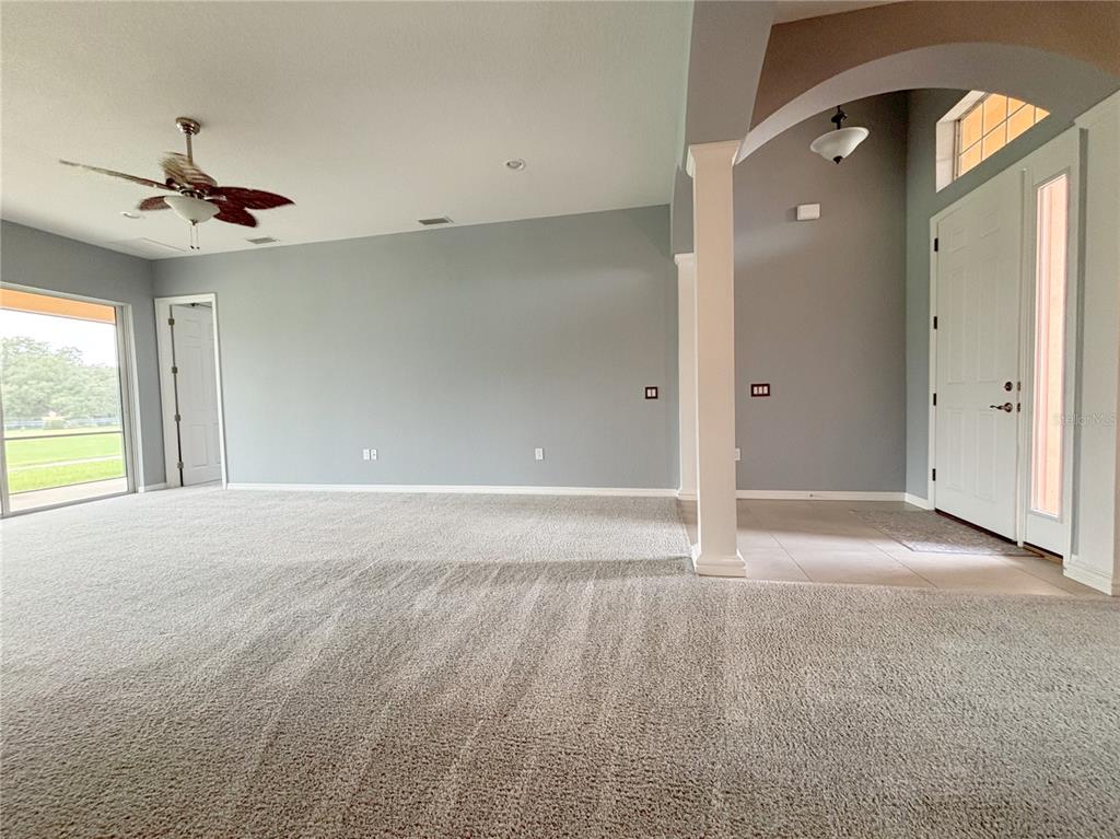 A carpeted living room features a ceiling fan, gray walls, and an arched entryway — 1124 SAWGRASS DRIVE, WINTER HAVEN, FL