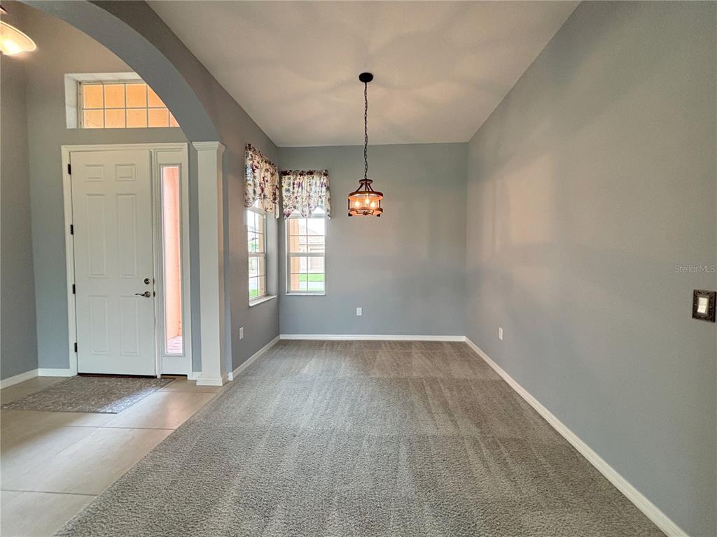 A dining area features gray walls, carpeted flooring, and a hanging light fixture — 1124 SAWGRASS DRIVE, WINTER HAVEN, FL