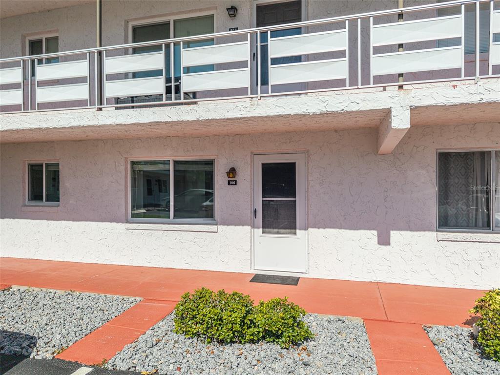 A ground-level apartment entrance with a white door, a window, and a balcony above — 1100 MARTINIQUE DRIVE UNIT 106, WINTER HAVEN, FL