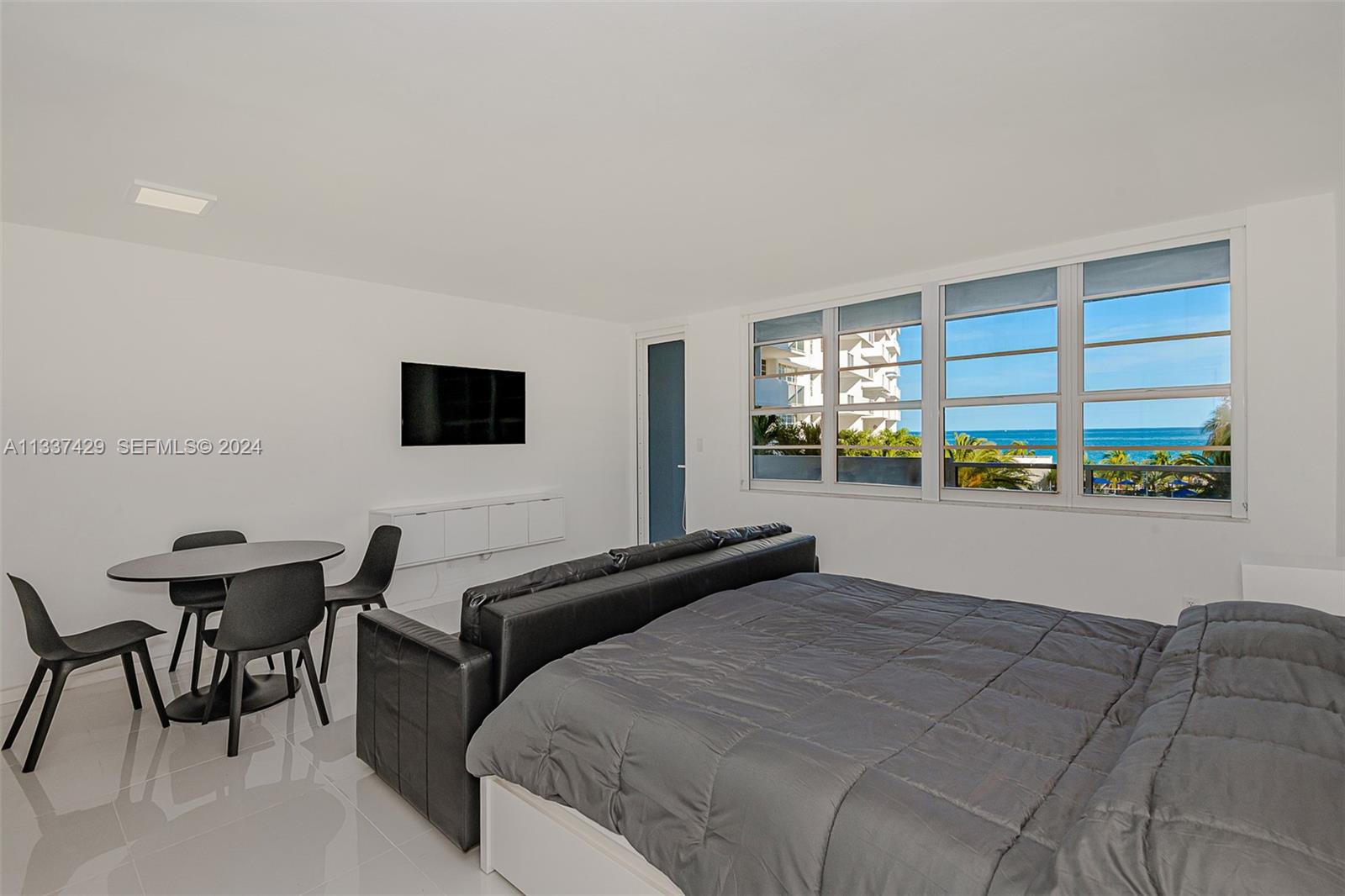 A bedroom with a bed, a small dining table, and a view of the ocean — 100 Lincoln Rd # 519, Miami Beach FL 33139, MIAMI BEACH, FL