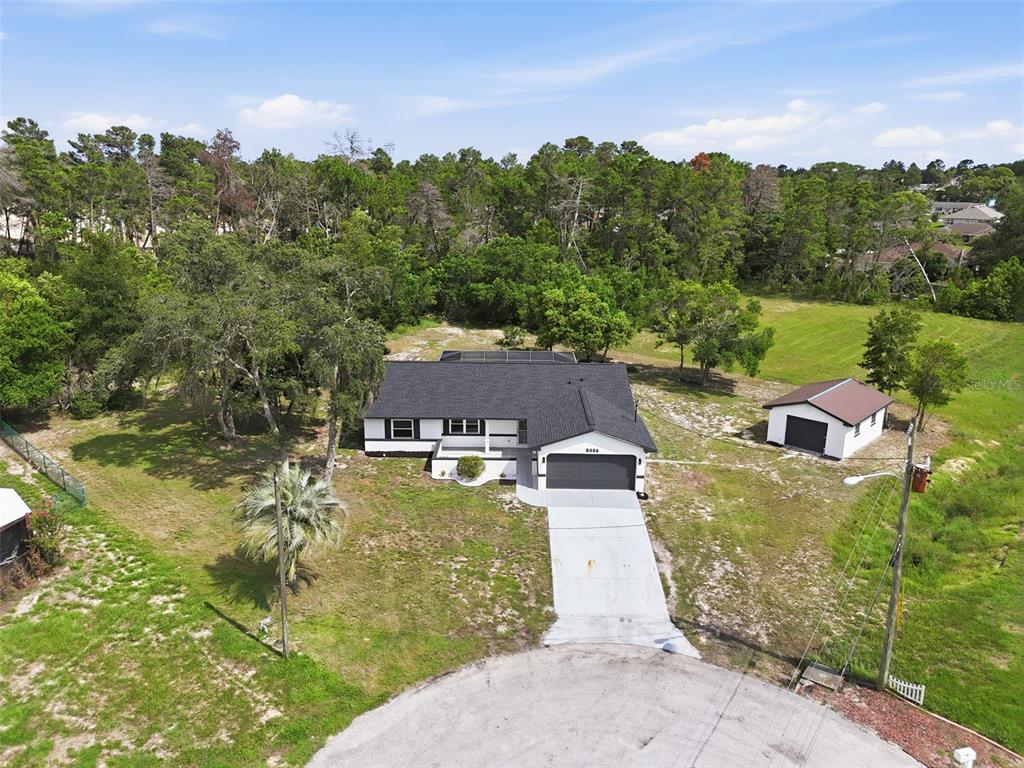 An aerial view shows a single-story house with a garage and detached shed on a lot — 6444 CROWLEY COURT, SPRING HILL, FL