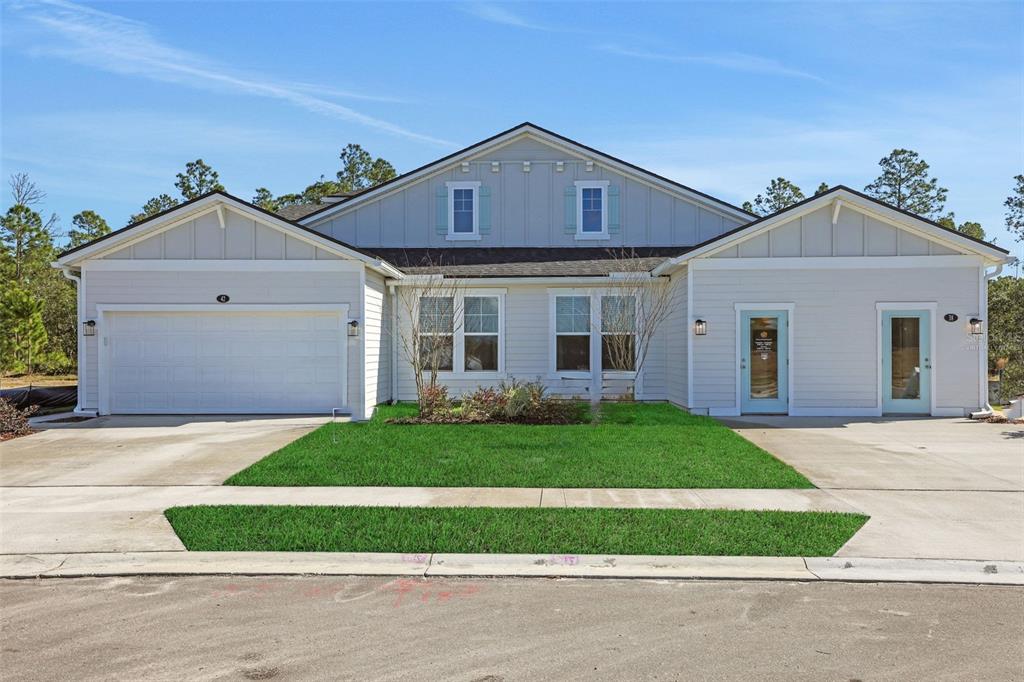 A light-colored duplex house features a two-car garage, two front doors, and a grassy lawn — 18 BIG PINE DRIVE, PALM COAST, FL