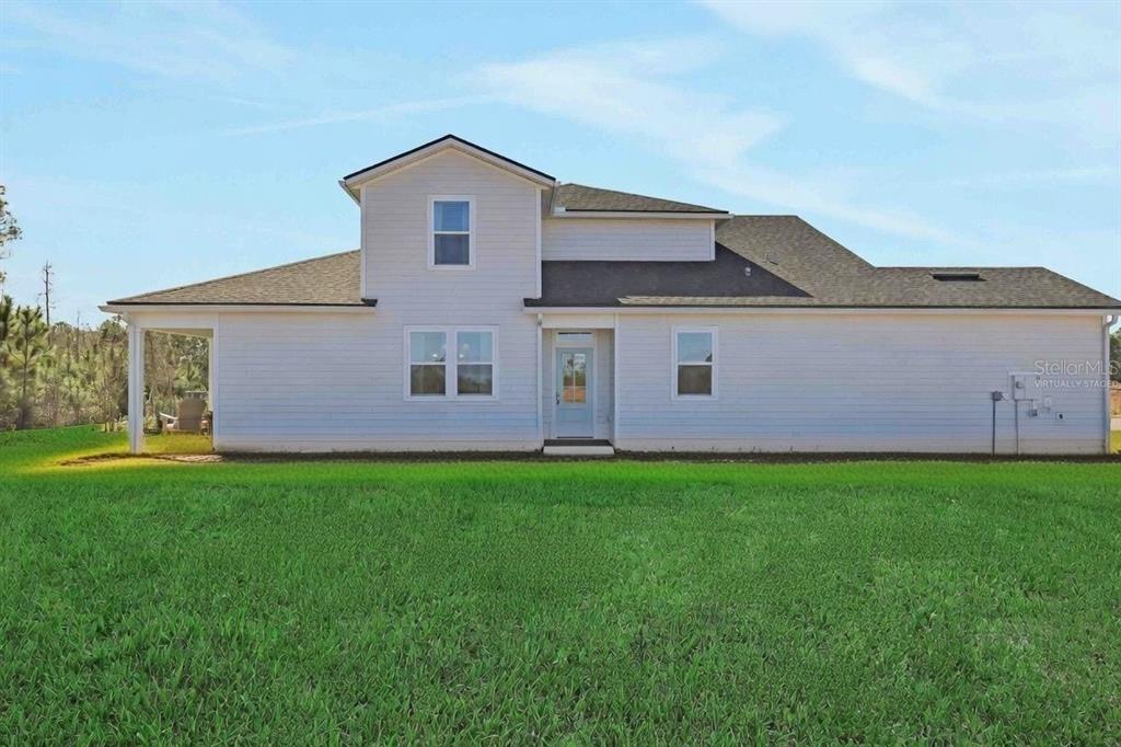 The exterior of a white, two-story house features a covered patio and a large lawn — 18 BIG PINE DRIVE, PALM COAST, FL