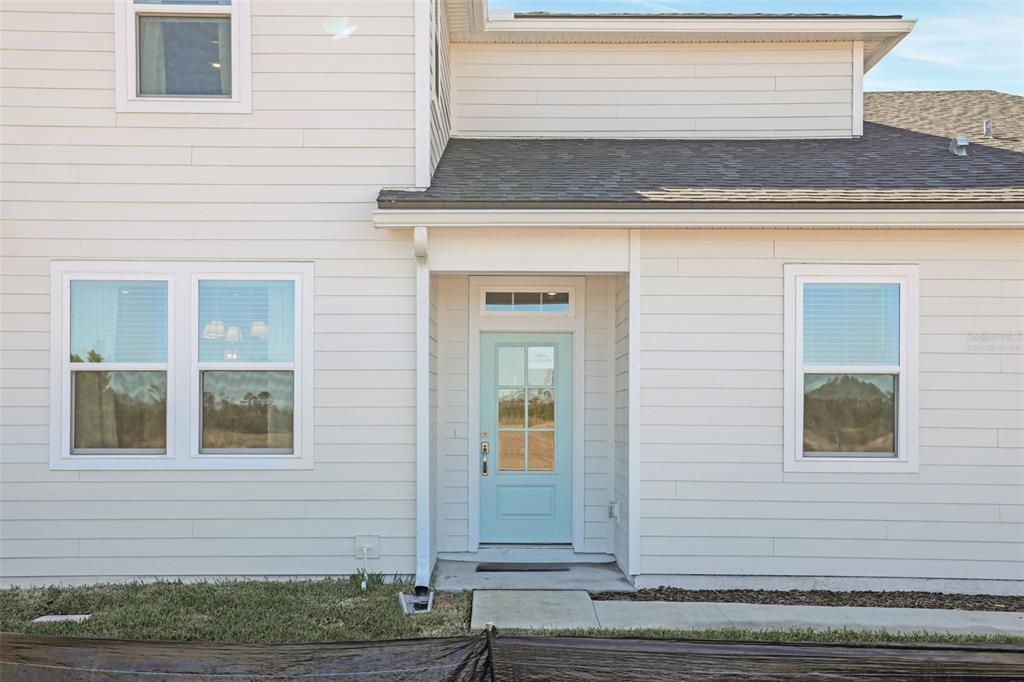 A light blue front door is centered on the exterior of a white-sided house — 18 BIG PINE DRIVE, PALM COAST, FL