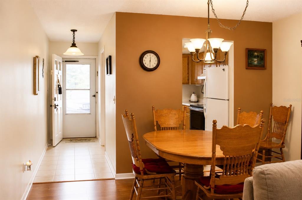 A dining area with a wooden table and chairs sits adjacent to an entryway and kitchen — 1662 S LAKE AVENUE UNIT 6, CLEARWATER, FL