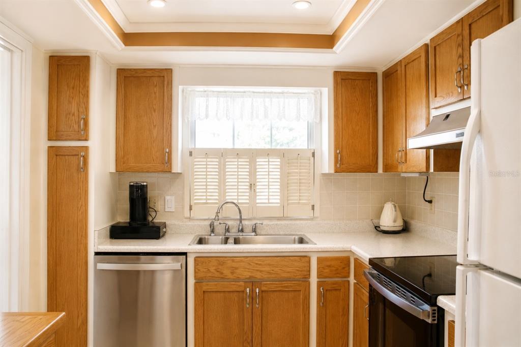 A kitchen with oak cabinets, stainless steel appliances, a window, and light-colored countertops — 1662 S LAKE AVENUE UNIT 6, CLEARWATER, FL