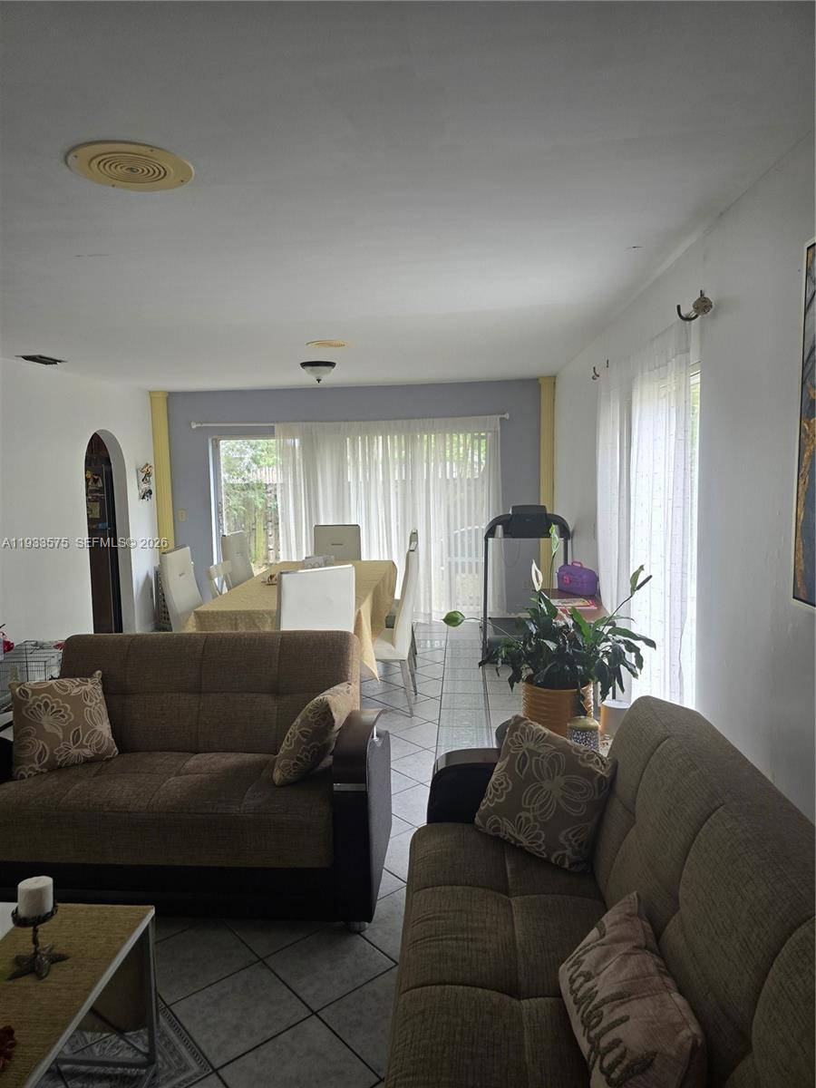 A living room with two brown sofas, a dining area, and a treadmill near windows — 12687 SW 146th St, Miami FL 33186, MIAMI, FL