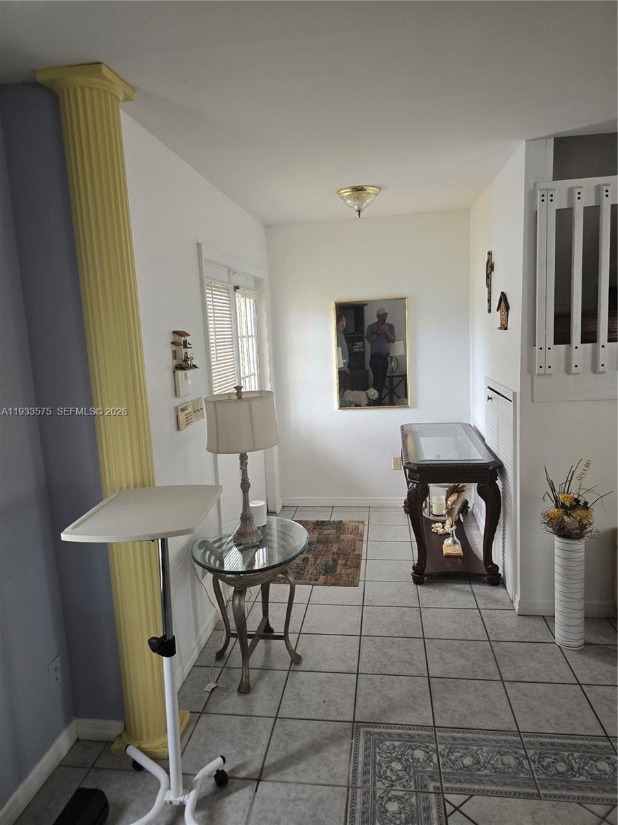 This entryway features a yellow column, tile flooring, a glass-topped table, and a wall mirror — 12687 SW 146th St, Miami FL 33186, MIAMI, FL